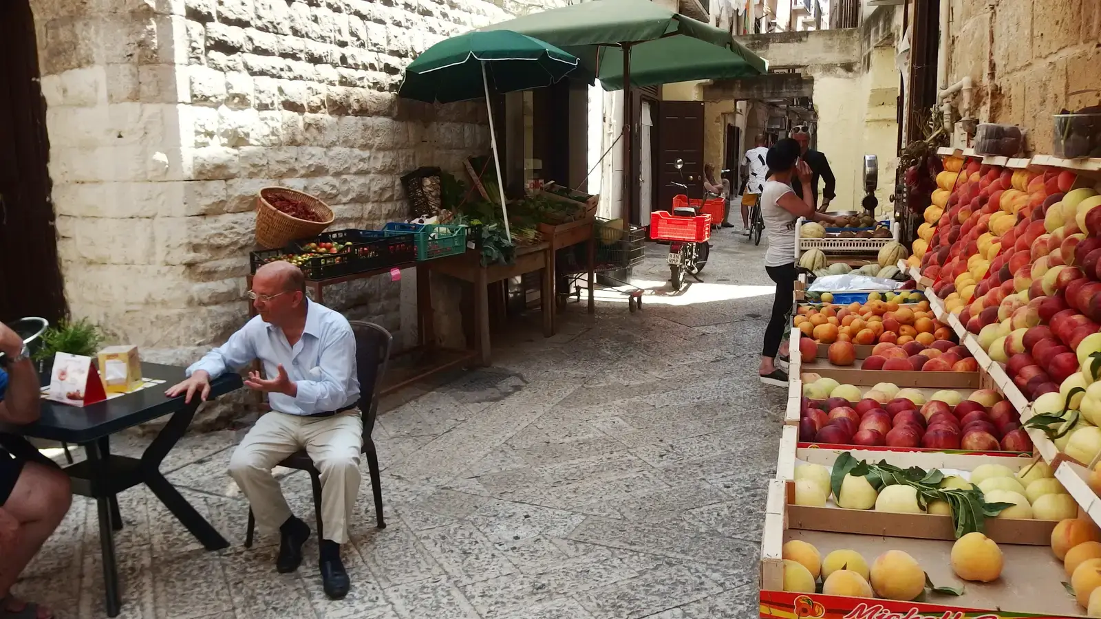 Una strada di Bari vecchia, con la bancarella della frutta e la gente